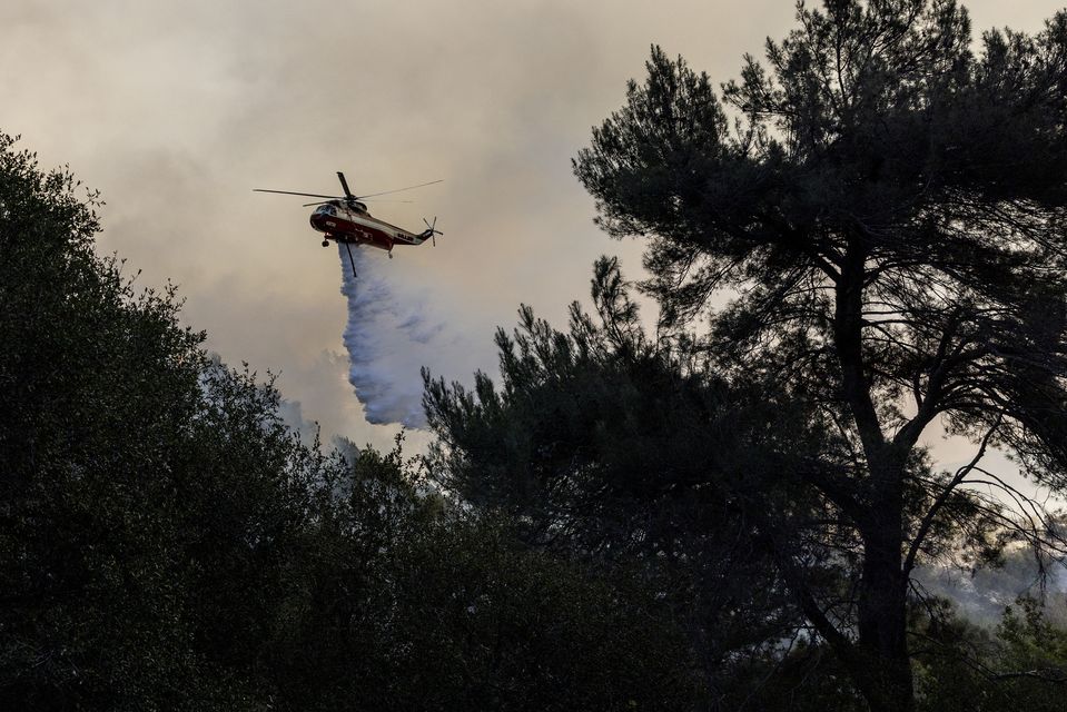 A firefighting helicopter releases water on a hot spot while battling the Palisades Fire in Topanga, California (Stephen Lam/San Francisco Chronicle via AP)