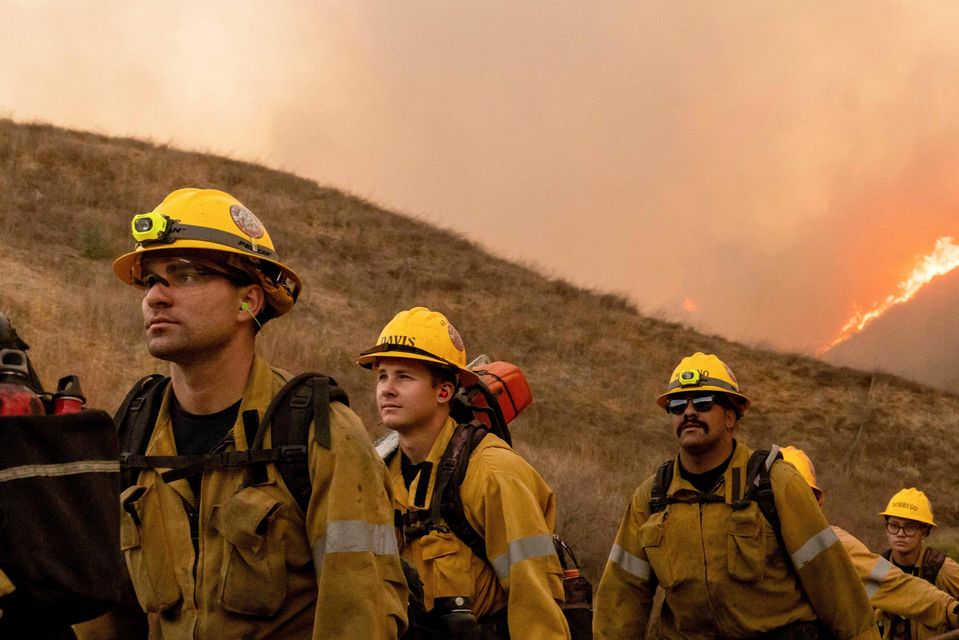 Fire crews walk as they battle the Kenneth Fire in the West Hills section of Los Angeles (Ethan Swope/AP)