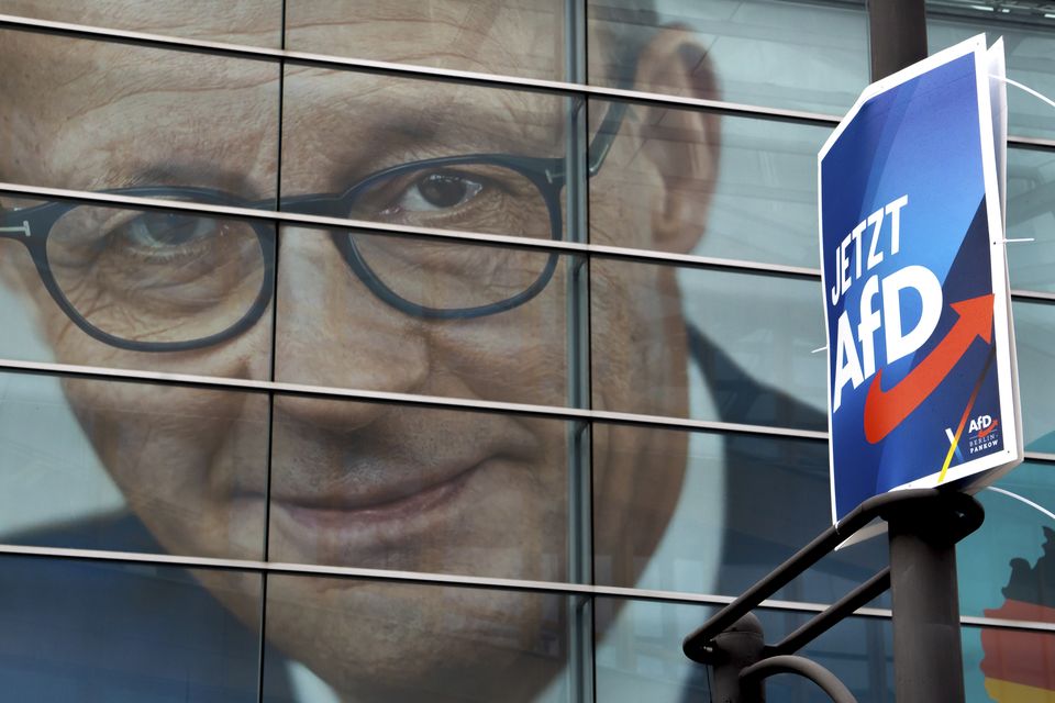 An election poster for AfD in front of a giant election poster showing chairman of the German Christian Democratic Party, Friedrich Merz (Michael Sohn/AP)