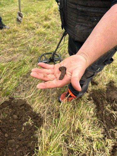 National Trust for Scotland employee Lorne MacLeod holding up an object thought to be from a piece of footwear, such as a heel plate (National Trust for Scotland/PA)