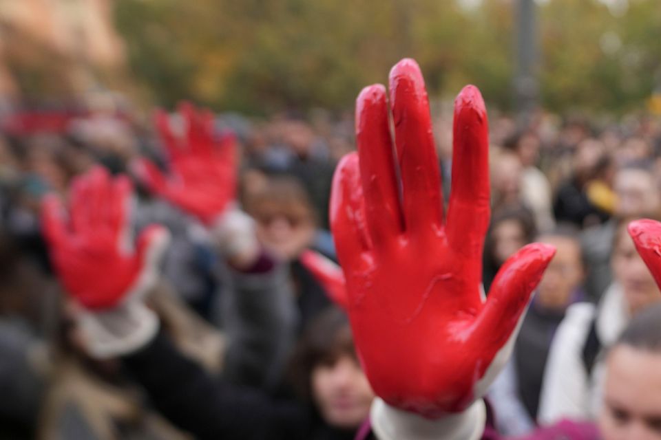 Protesters shout slogans with red paint on their hands (Darko Vojinovic/AP)