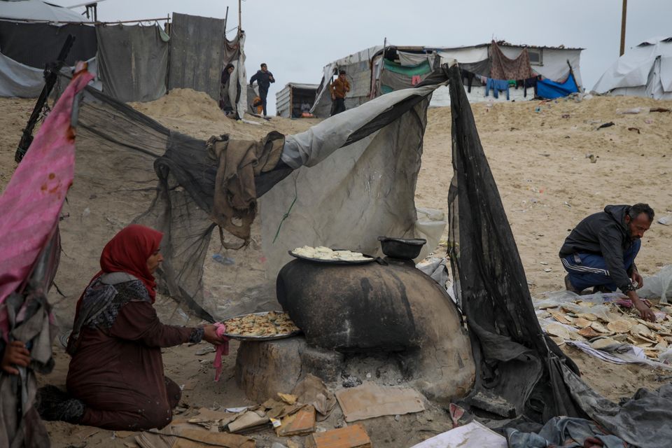 Mona Al-Zebda, displaced from Gaza City, bakes bread at a tent camp for displaced Palestinians at the Muwasi, Rafah (Jehad Alshrafi/AP)