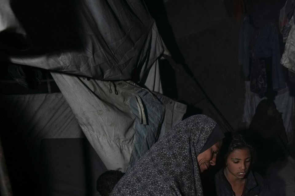 A displaced family sit round the fire in their tent at a camp in Deir al-Balah, Gaza Strip (Abdel Kareem Hana/AP)