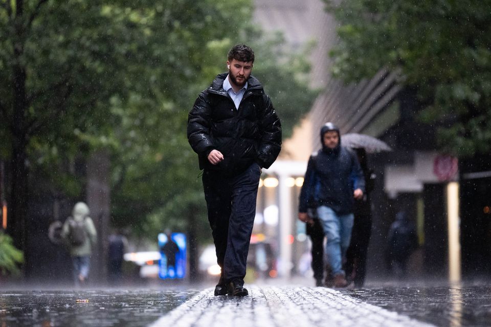 People wearing waterproof coats, hoods and carrying umbrellas walking in the rain in London (James Manning/PA)