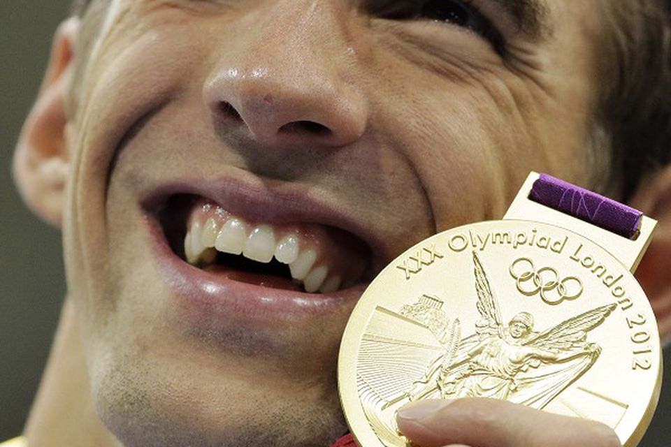 Michael Phelps poses with his gold medal for the men's 4x200-metre freestyle relay swimming final (AP/Matt Slocum)