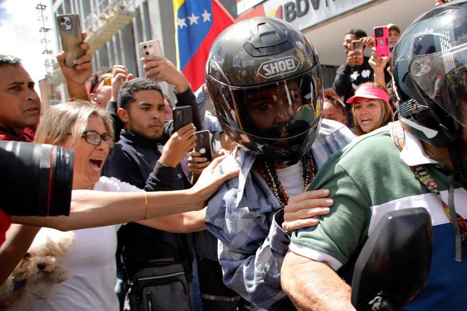 Ms Machado is driven away on a motorbike at the end of the rally (Cristian Hernandez/AP)