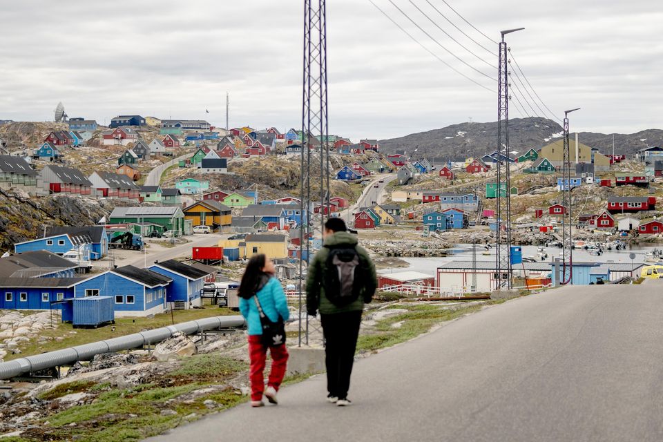 People walk in the town of Aasiaat in western Greenland (Ida Marie Odgaard/AP)