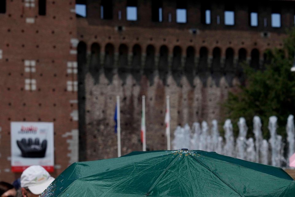 Tourists shelter from the sun in front of the Sforzesco Castle in Milan, Italy (AP Photo/Luca Bruno)