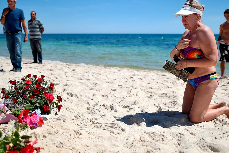 Holidaymakers react as people lay flowers on Marhaba beach, where 38 people were killed in a terrorist attack last Friday, on June 30, 2015 in Sousse, Tunisia. British police have been deployed to the area as part of one of the biggest counter terror operations since the London bombings on July 7, 2005. (Photo by Jeff J Mitchell/Getty Images)