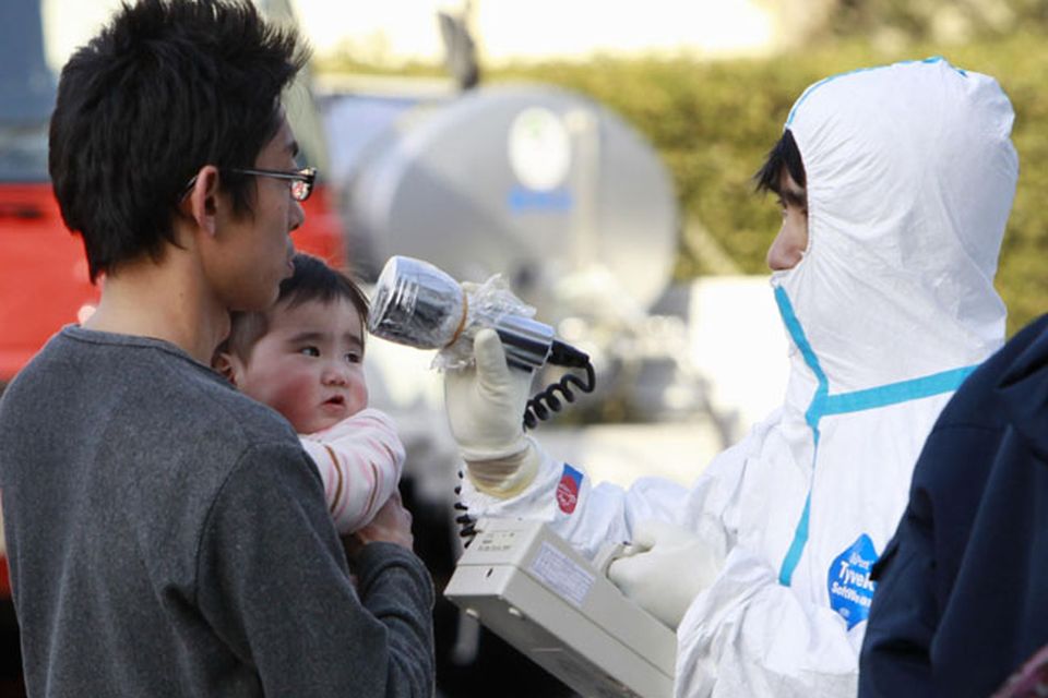 A man holds his baby as they are scanned for levels of radiation in Koriyama, Fukushima Prefecture, Japan, Sunday, March 13, 2011. Friday's quake and tsunami damaged two nuclear reactors at a power plant in the prefecture, and at least one of them appeared to be going through a partial meltdown, raising fears of a radiation leak. (AP Photo/Mark Baker)
