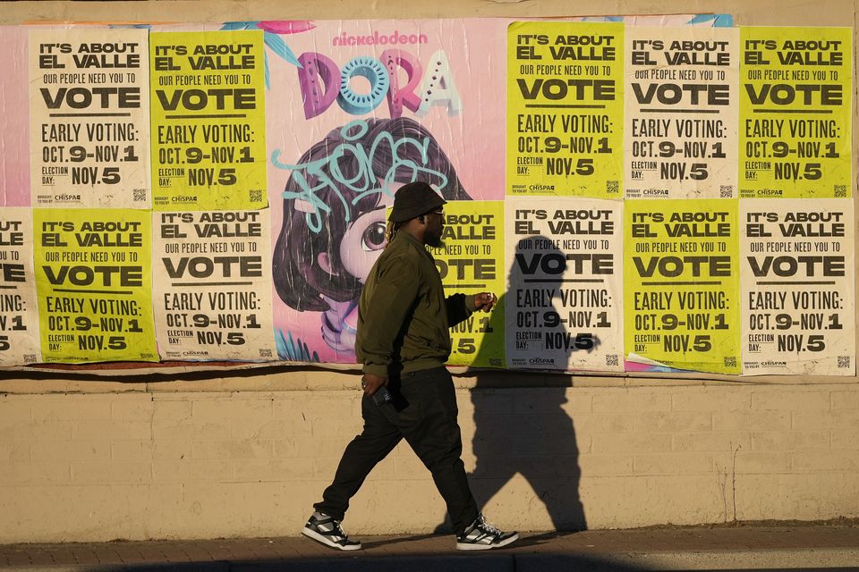 A man walks past a wall covered with voting flyers in Phoenix, Arizona (Matt York/AP)