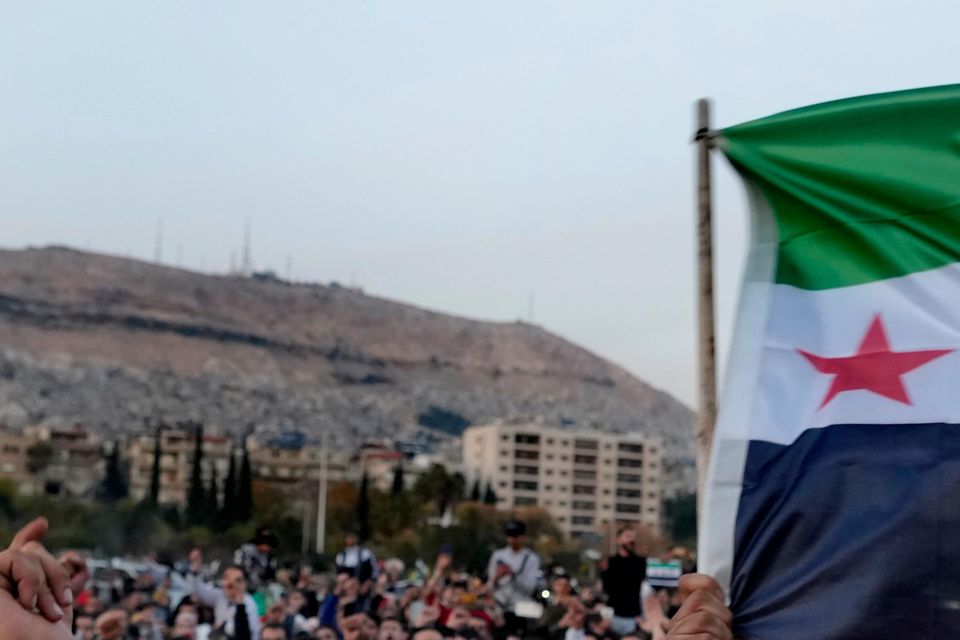 Syrian citizens wave the revolutionary flag and shout slogans as they celebrate the fall of Bashar Assad in Damascus (Hussein Malla/AP)