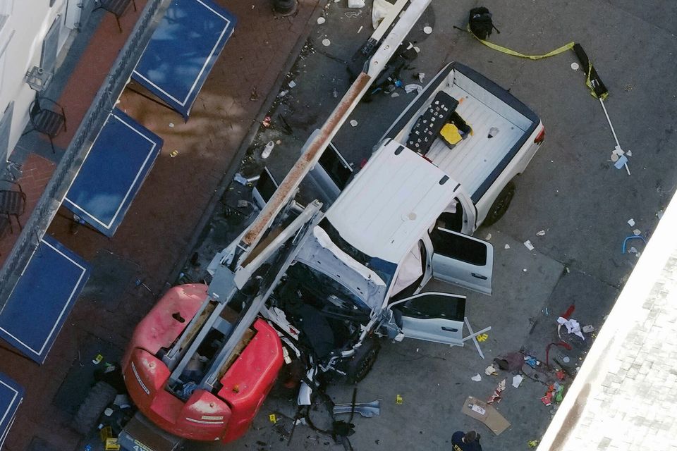 A black flag with white lettering lies on the ground rolled up behind a pickup truck that a man drove into a crowd in New Orleans (Gerald Herbert/AP)