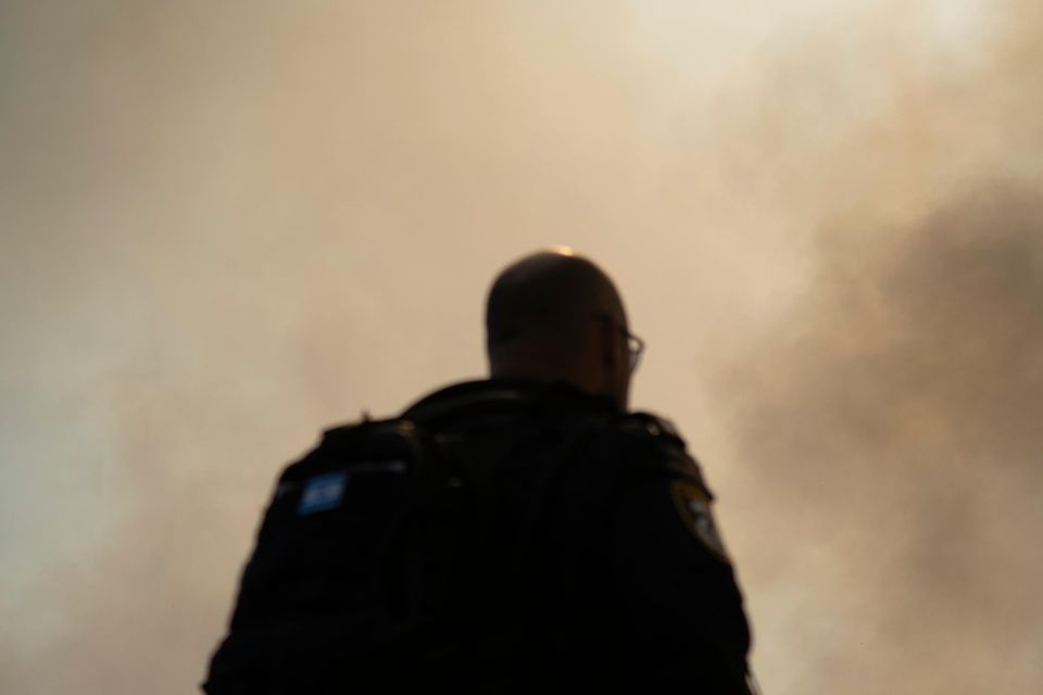 Israeli police stand next to a site of a fire after a rocket, fired from Lebanon, hit an area near the town of Rosh Pinna, northern Israel, on Sunday (Leo Correa/AP)