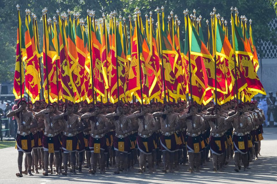 Sri Lankans dressed as ancient soldiers carry their national flags during the country’s Independence Day (Eranga Jayawardena/AP)