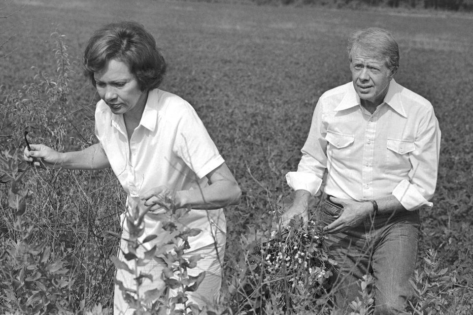 President Jimmy Carter carries a peanut plant as he follows his wife Rosalynn from the field in Webster County, Georgia (Jim Wells/PA)