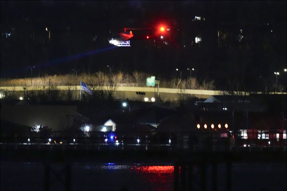 A helicopter uses its searchlight as it flies above the Potomac River near Ronald Reagan Washington National Airport (AP Photo/Alex Brandon)