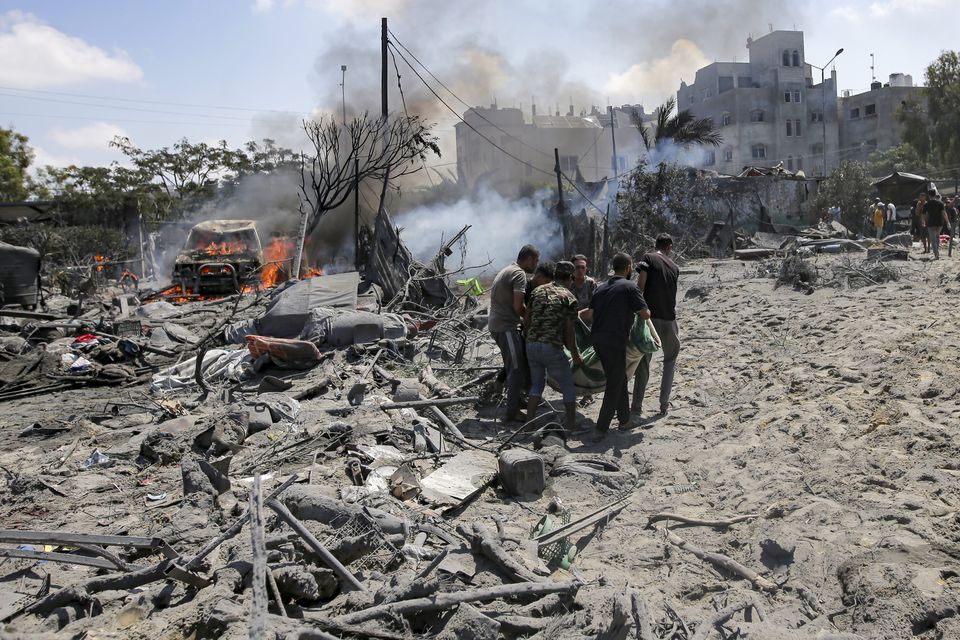 Palestinians evacuate a body from a site hit by an Israeli bombardment on Khan Younis, southern Gaza Strip, on July 13 (Jehad Alshrafi/AP)