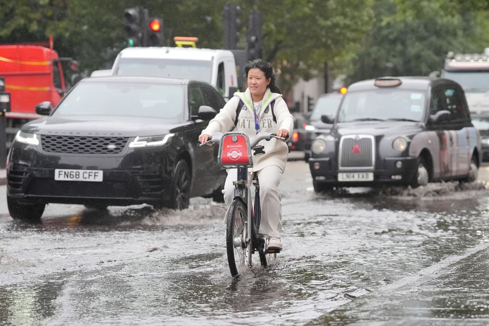 A cyclist rides through a puddle on Euston Road in London (Jonathan Brady/PA)