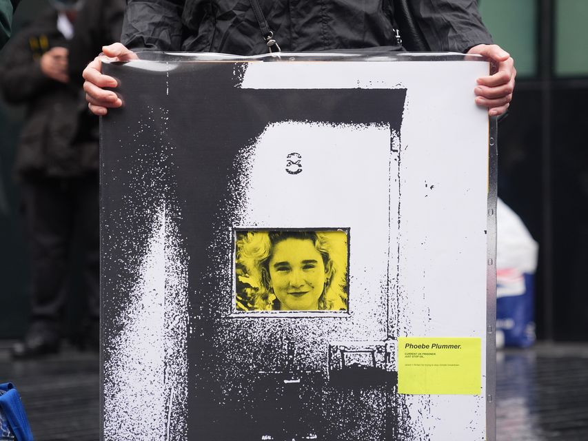 A Just Stop Oil activist holds up a banner of Phoebe Plummer outside Southwark Crown Court (James Manning/PA)