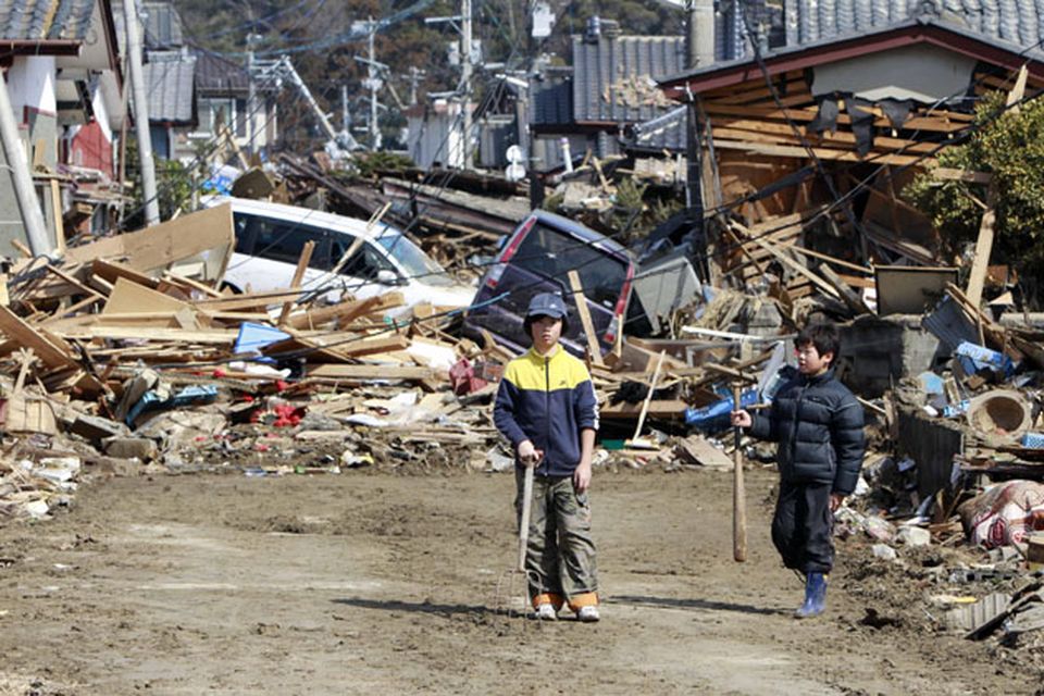 Young residents of the seaside town of Toyoma, northern Japan, walk amongst the debris around their homes Monday, March 14, 2011, three days after a giant quake and tsunami struck the country's northeastern coast. (AP Photo/Mark Baker)