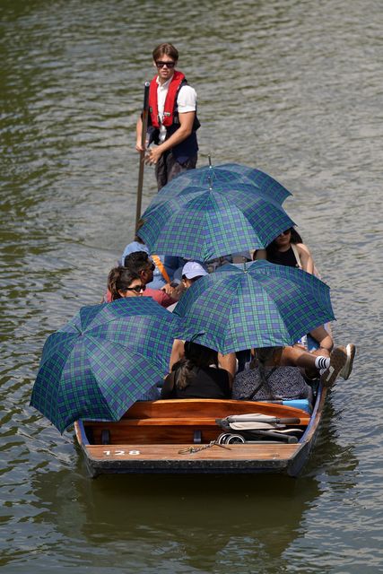 People shelter from the sun under umbrellas as they take a punt tour along the River Cam in Cambridge (Joe Giddens/PA)