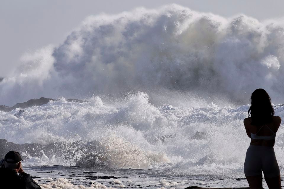 People watch as huge swells hit the beaches on the Gold Coast (Jason O’Brien/AAP Image/AP)