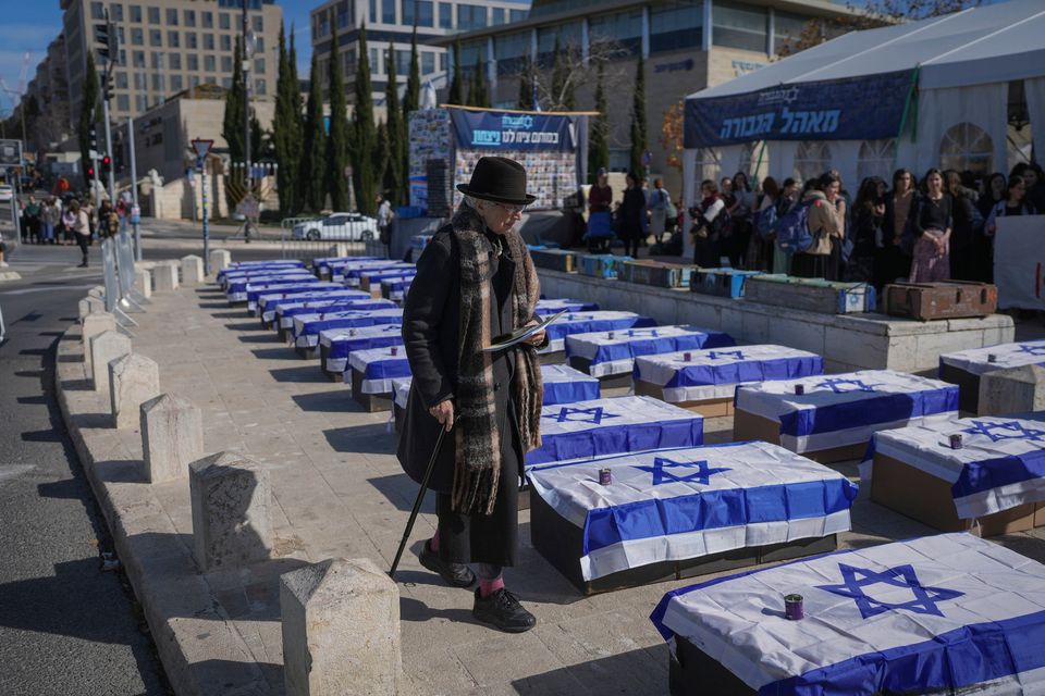 A woman in Jerusalem walks by mock coffins lining a street and covered with Israeli flags that are meant to symbolise the price Israel will pay for agreeing to a ceasefire with Hamas (AP Photo)