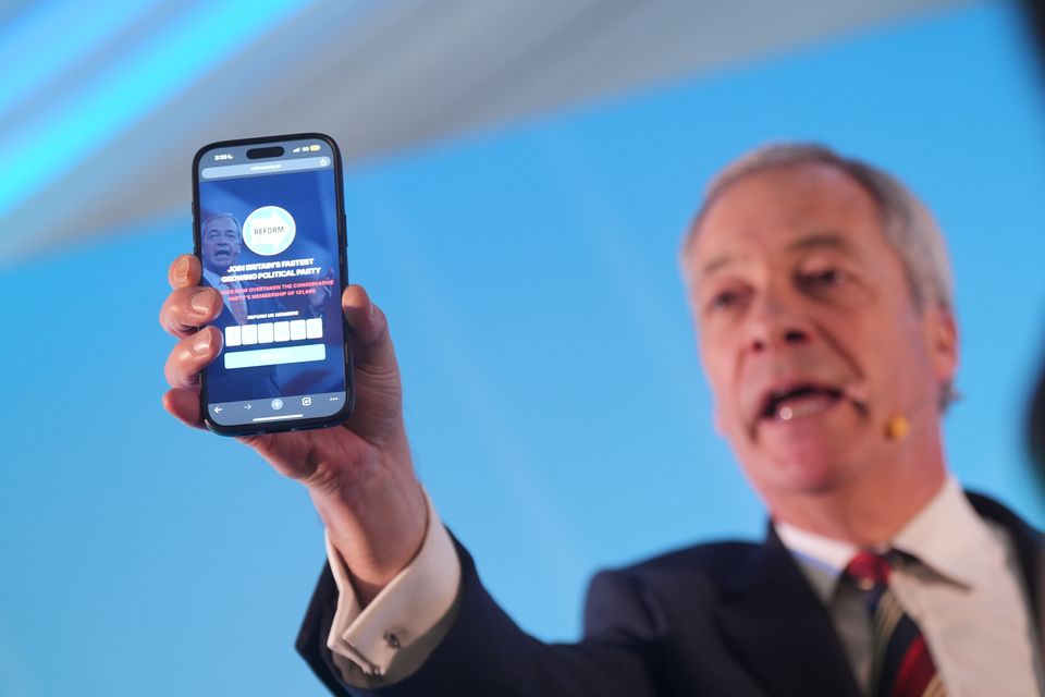 Reform UK leader Nigel Farage holding a phone displaying the number of Reform UK party members (Yui Mok/PA)